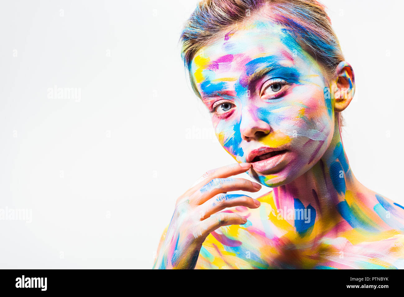 Attraente ragazza con luminosi colorati arte del corpo toccando il labbro isolato su bianco Foto Stock