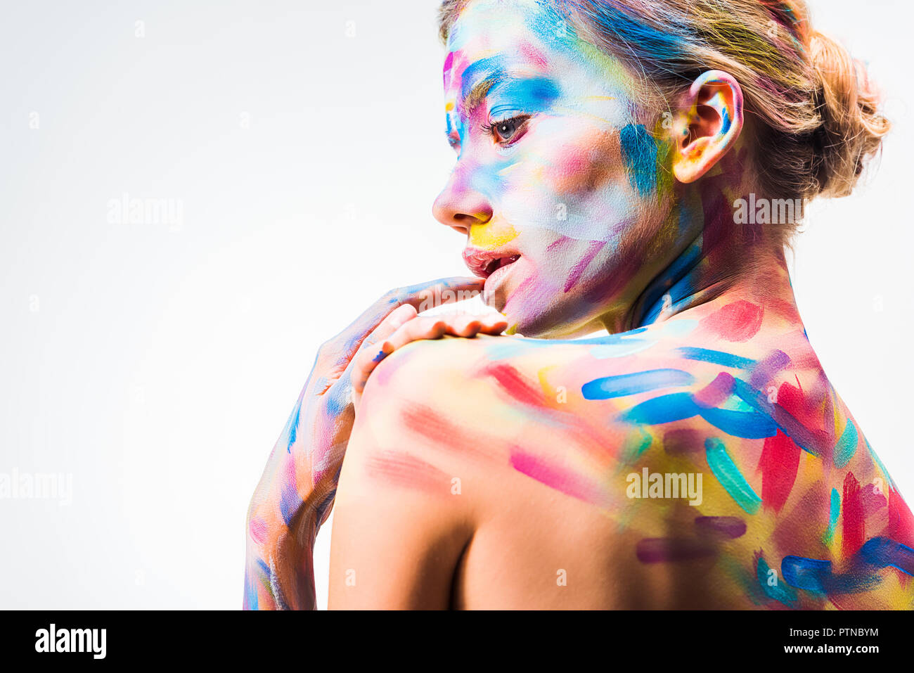 Vista laterale della ragazza attraente con colorate luminose arte del corpo toccando il labbro isolato su bianco Foto Stock