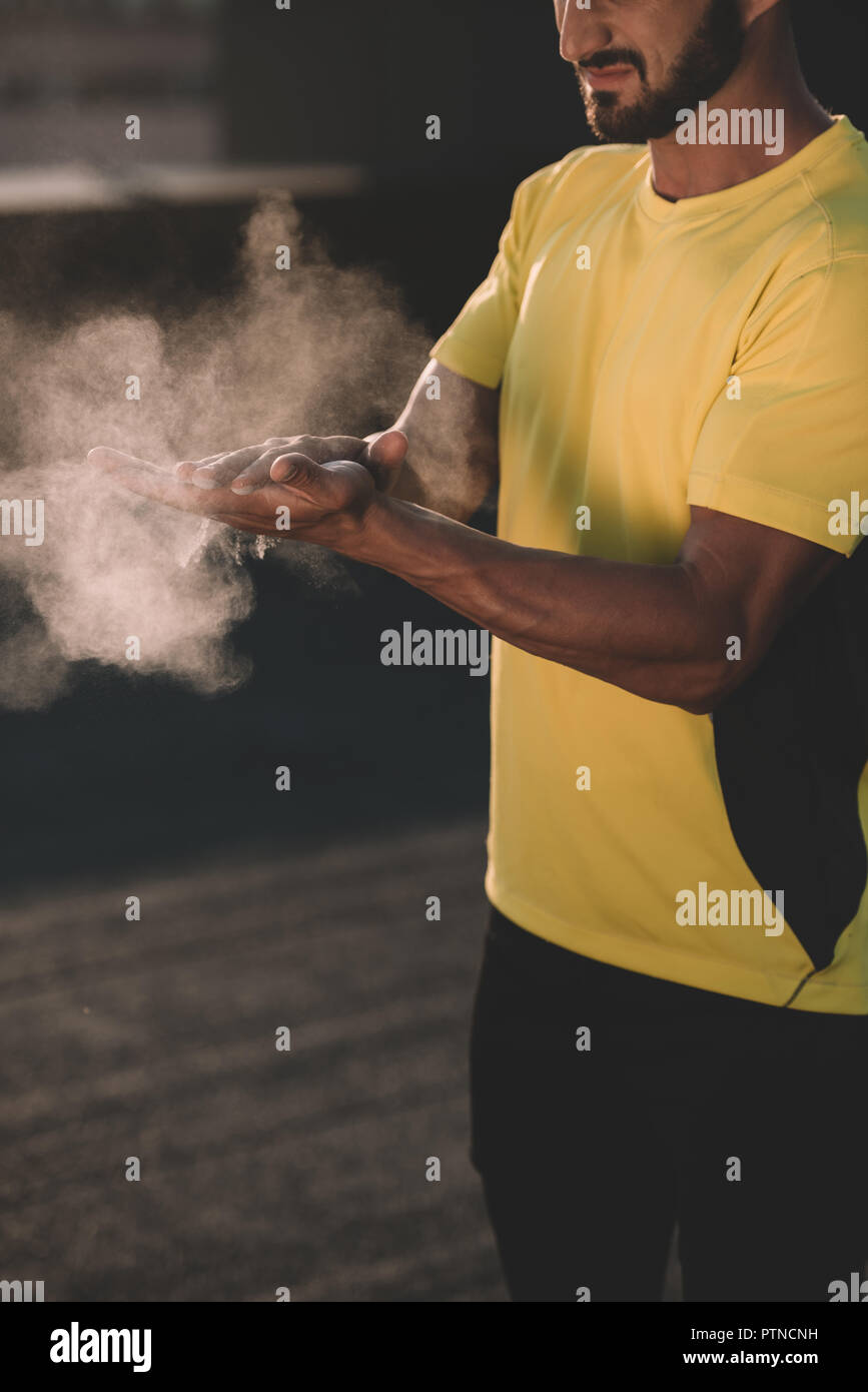 Immagine ritagliata di uomo sportivo battendo le mani con talco in polvere sul tetto Foto Stock