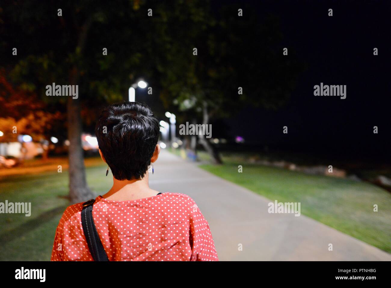 Una donna cammina da sola giù per un sentiero di notte, Townsville, Queensland, Australia Foto Stock