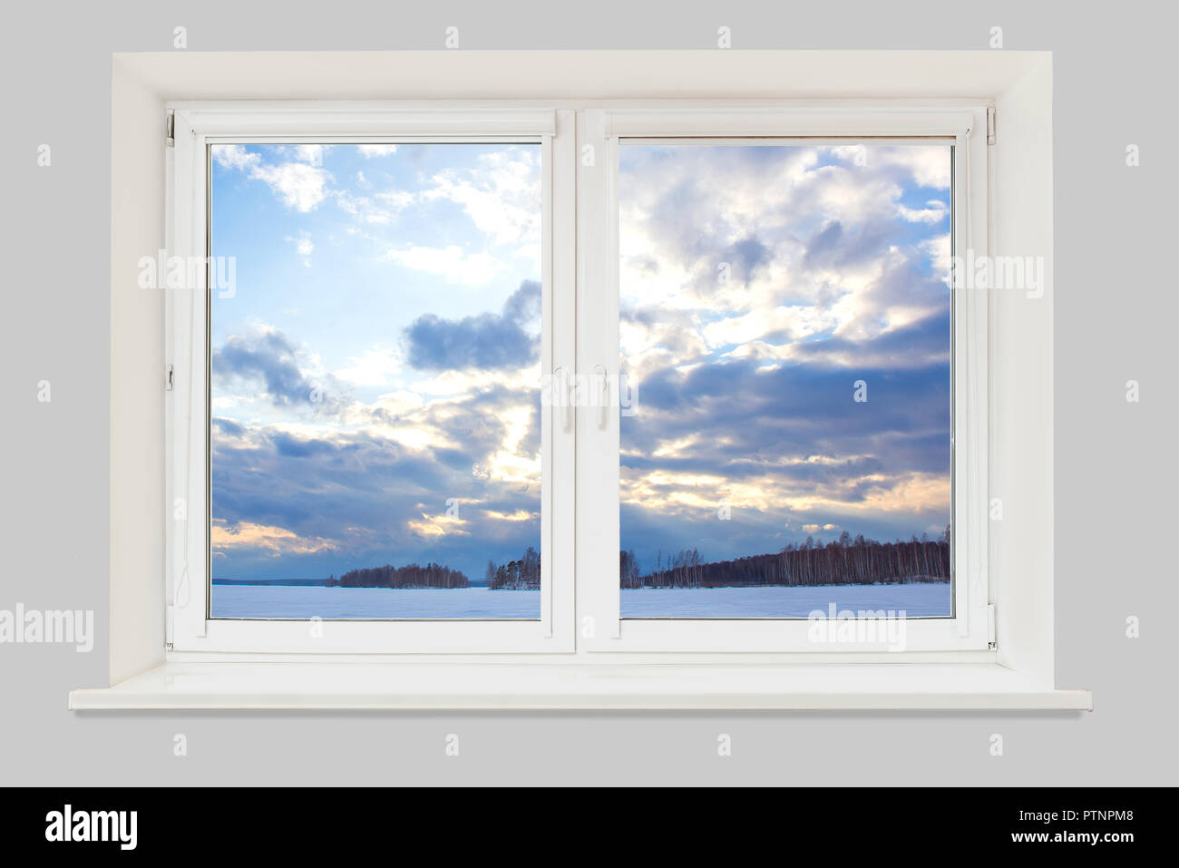 La vista dalla finestra per il paesaggio invernale con un lago ghiacciato, una foresta e una sera cielo nuvoloso Foto Stock