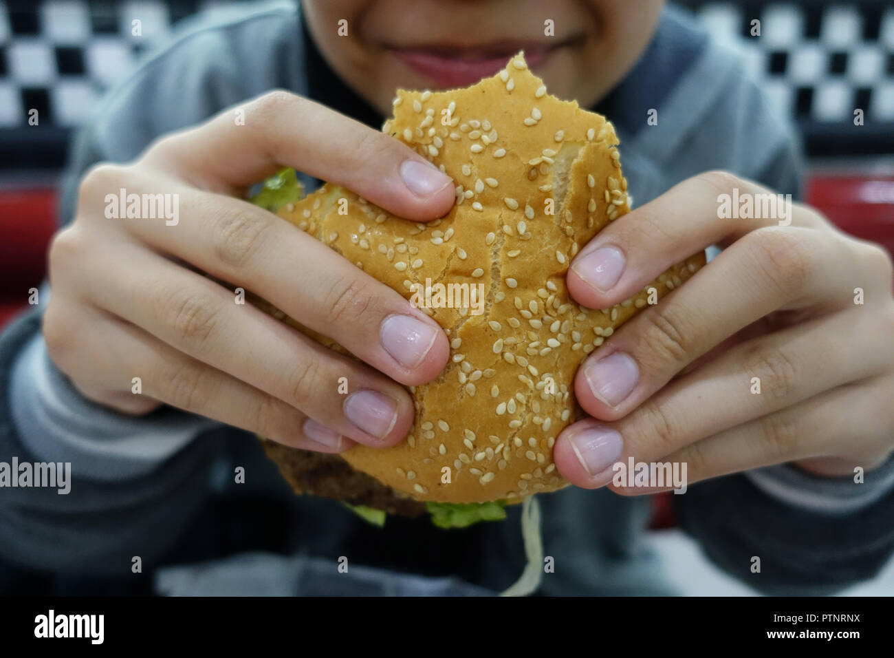 Giovane mangiare hamburger Foto Stock