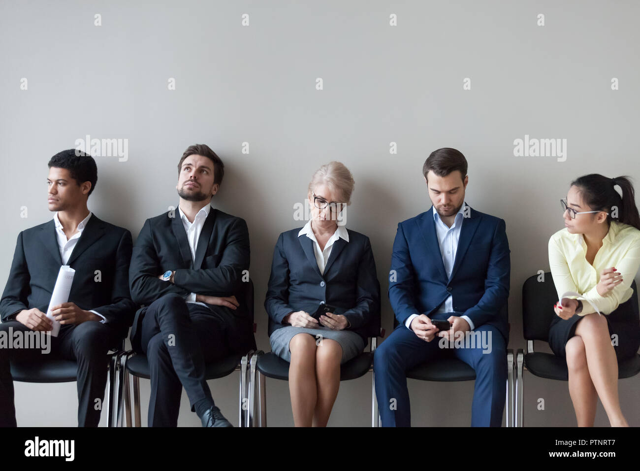 Diversi candidati lavoro seduta in attesa nella coda per il colloquio Foto Stock
