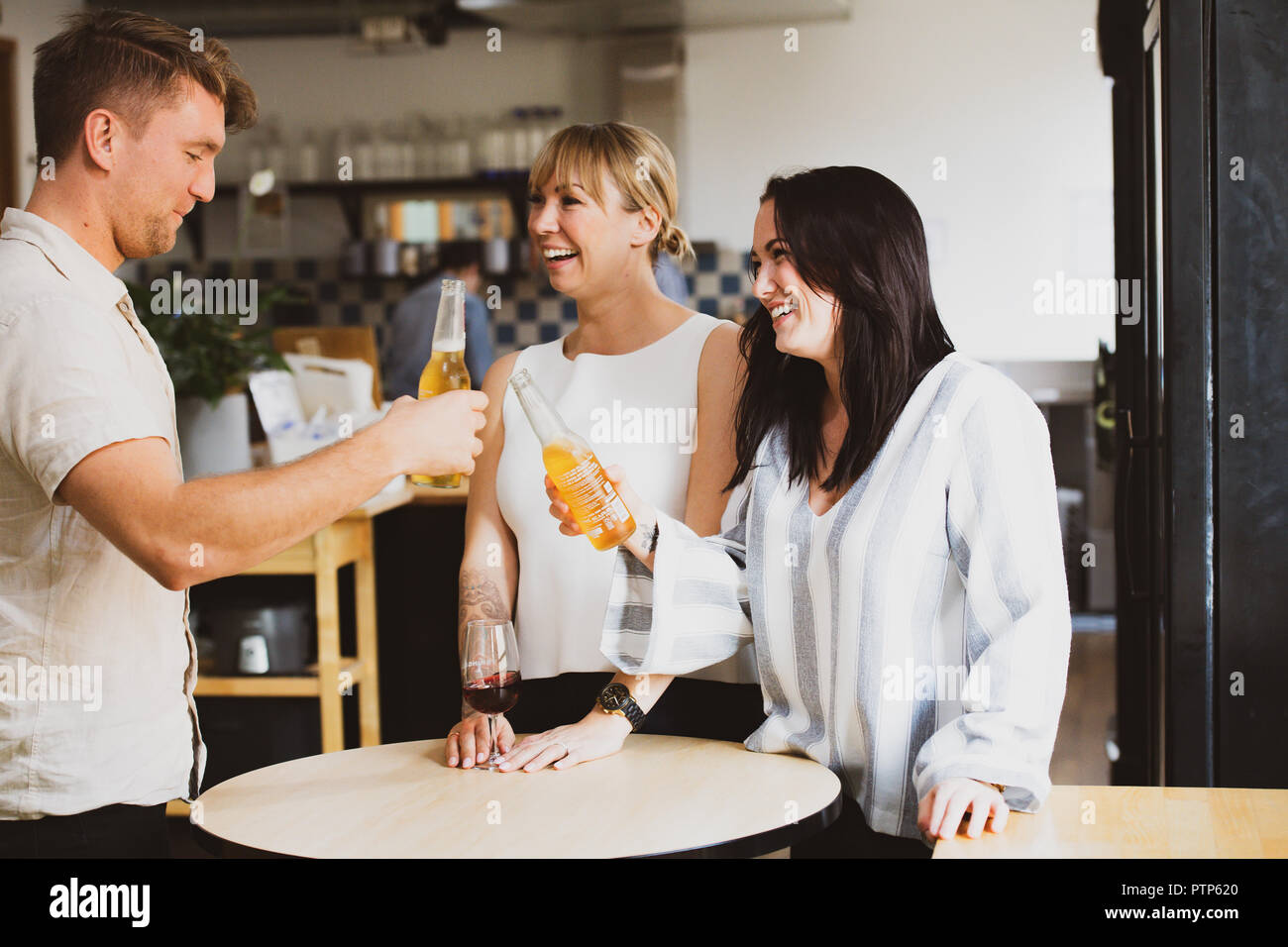 Gli imprenditori di rilassarsi dopo una giornata di duro lavoro con un paio di drink in un co-spazio di lavoro Foto Stock Gli imprenditori di rilassarsi dopo una giornata di duro lavoro con un paio di drink in un co-spazio di lavoro Foto Stock