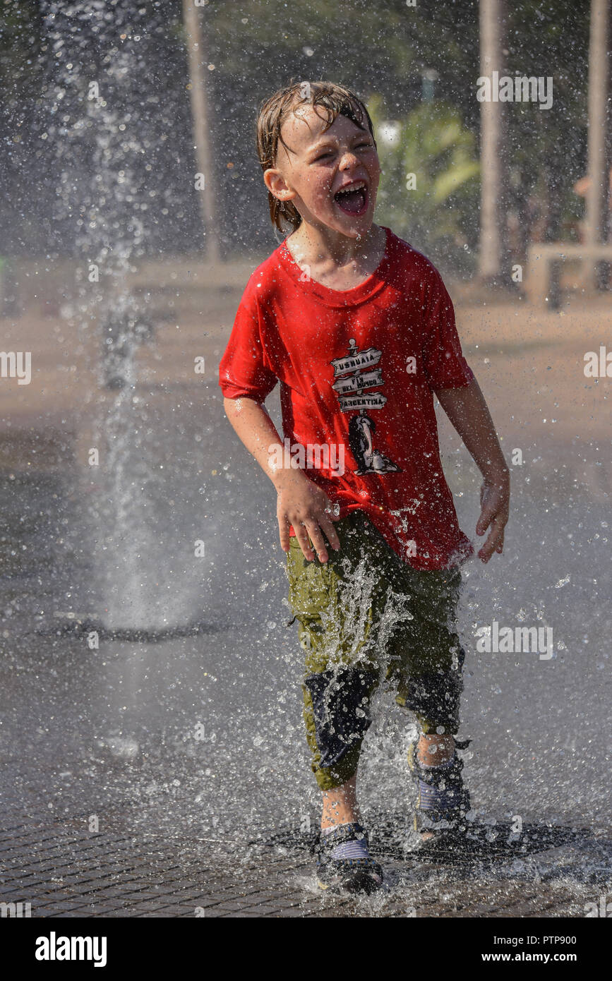 Il ragazzo si erge in una fontana e viene spruzzato, Puerto Iguazú, in Argentina Foto Stock