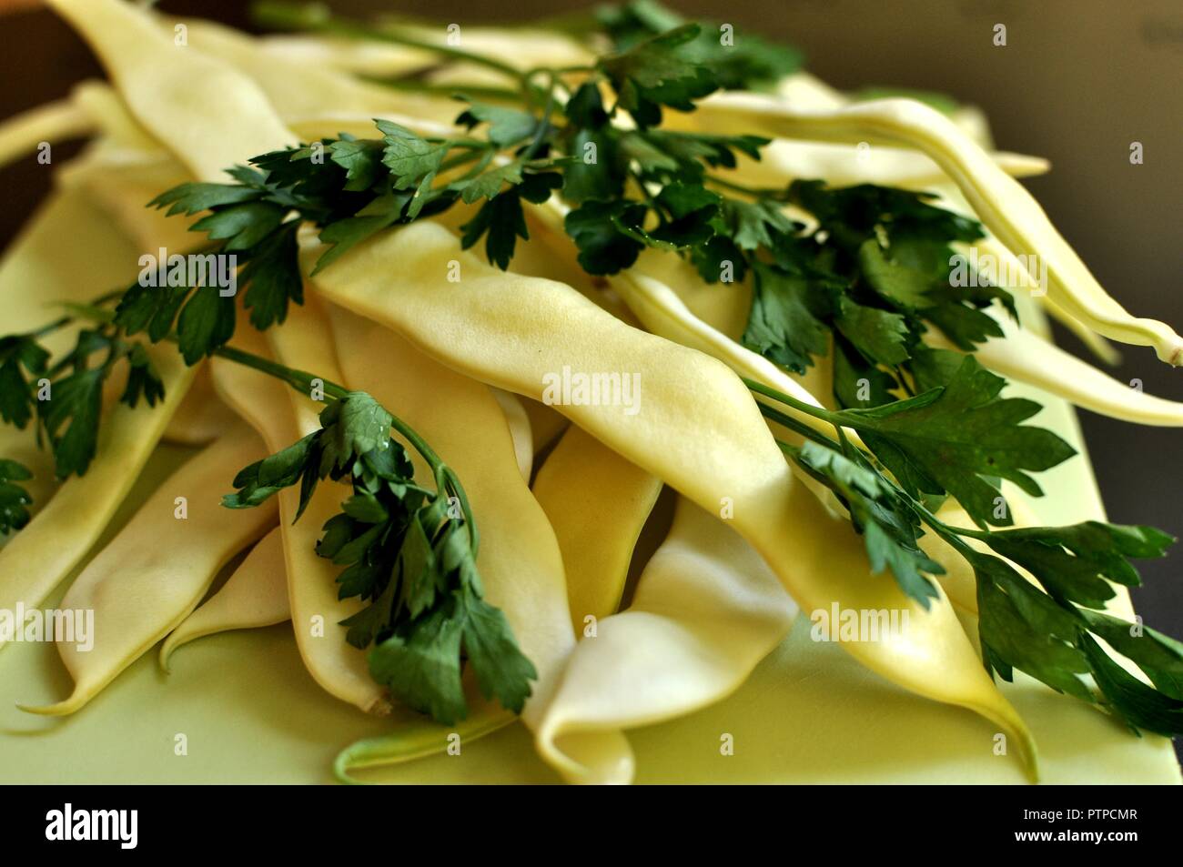 Close up della stringa verde fagioli freschi conditi con prezzemolo e bianco su sfondo nero. Parte anteriore vista superiore Foto Stock