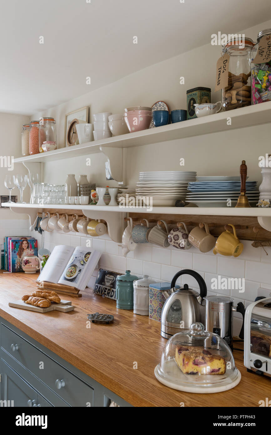 Le tazze da appendere in scaffali aperti con gli elettrodomestici in cucina del xviii secolo Norfolk cottage Foto Stock