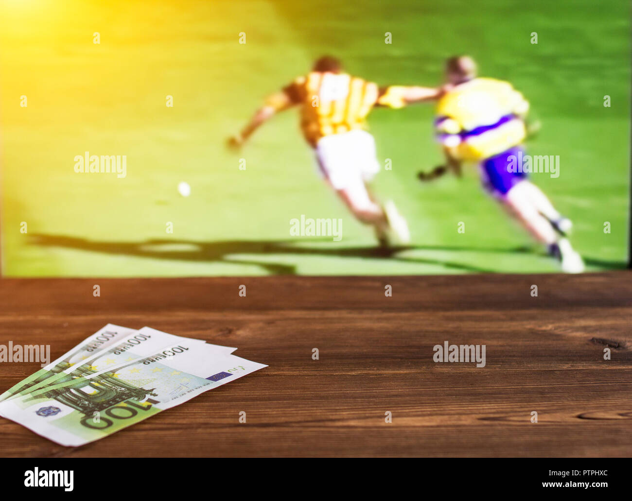 Euro denaro sullo sfondo di una TV in cui lo sport è mostrato nel gioco di  hockey irlandese, scommesse sportive, curling Foto stock - Alamy