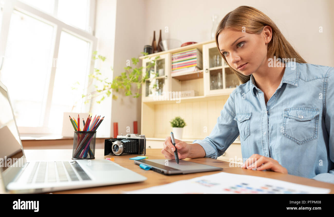 Donna artista grafico utilizza una tavoletta grafica, la progettazione e il disegno al computer, lavorare a casa, libero professionista Foto Stock