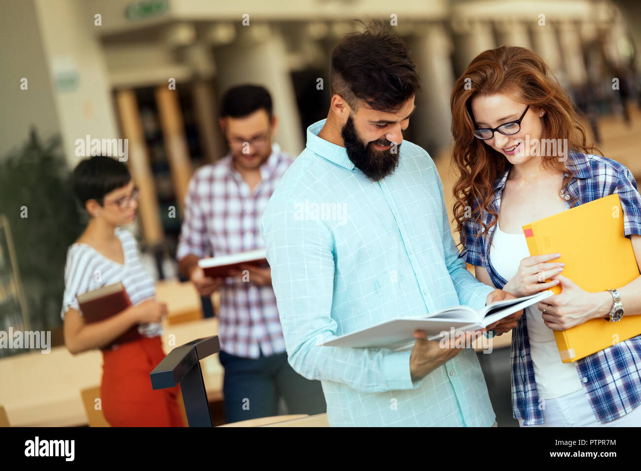 Contenti i giovani studenti universitari che studiano con libri in biblioteca Foto Stock