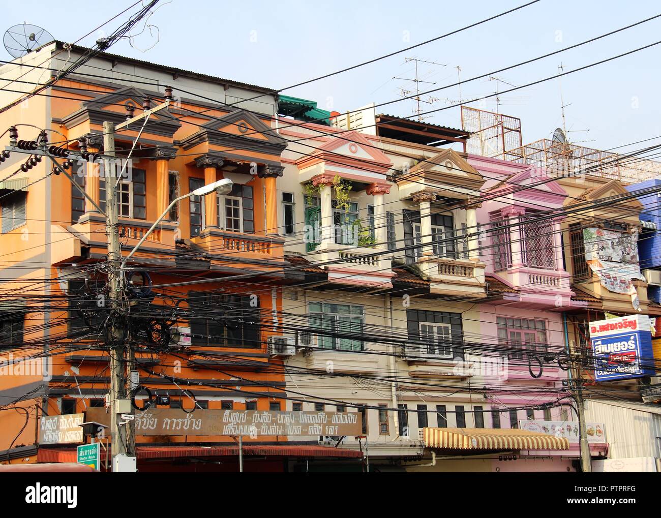 Case in strada di Bangkok con un sacco di cavi elettrici Foto Stock