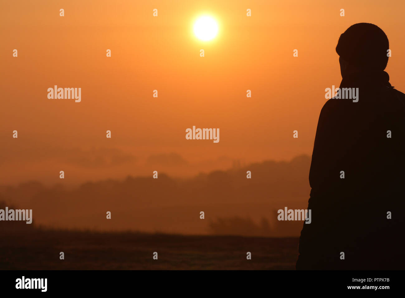 Una silhouette di un uomo guardando il sunrise Foto Stock