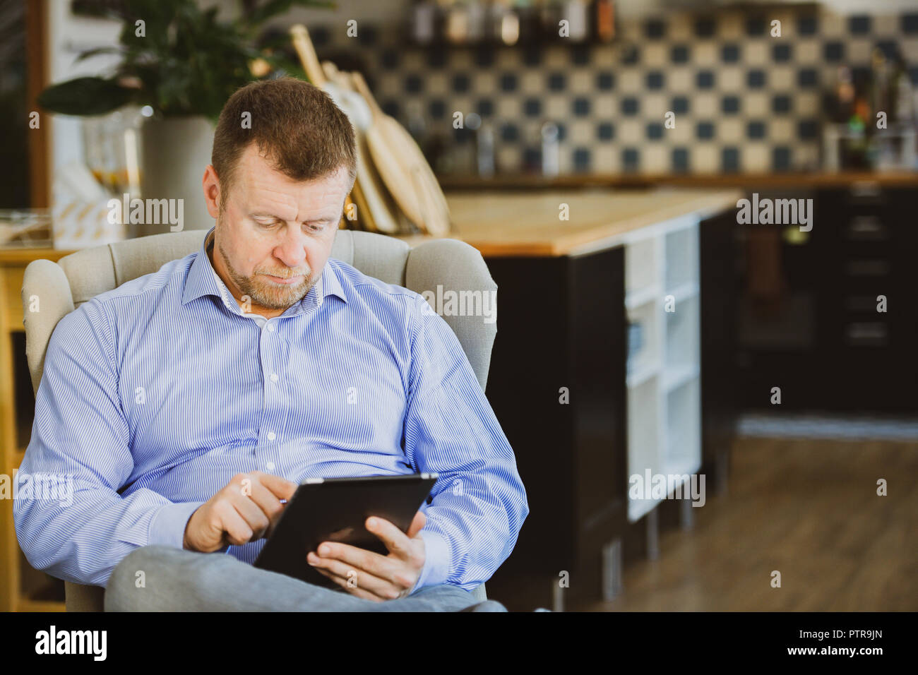 Imprenditore lavorando su un tablet in una co-spazio di lavoro che funzioni come il suo ufficio Foto Stock