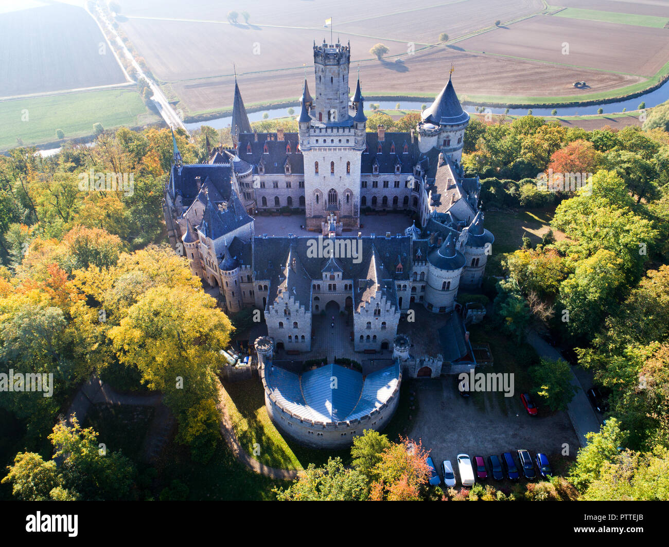 Pattensen, Bassa Sassonia. Undicesimo oct, 2018. Il Castello di Marienburg si erge nella luce del sole di mattina in mezzo autunnali alberi scoloriti (fotografia aerea con drone). Re Giorgio V di Hannover ha avuto il neo-gotico residence costruito tra il 1858 e il 1869. 150 anni più tardi il castello è di proprietà privata da Ernst August principe di Hannover Jr e una popolare meta escursionistica nella regione di Hannover. Credito: Julian Stratenschulte/dpa/Alamy Live News Foto Stock
