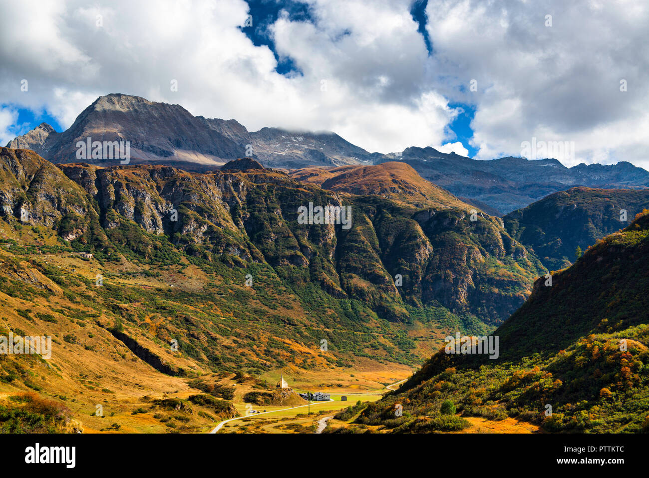 Colori autunnali in Val Formazza in un pomeriggio soleggiato con le montagne e il cielo nuvoloso in background Foto Stock