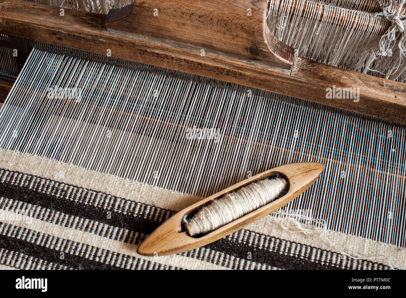 Il telaio di tessitura e la navetta dell'ordito. Sfondo di tessitura e campione. Foto Stock
