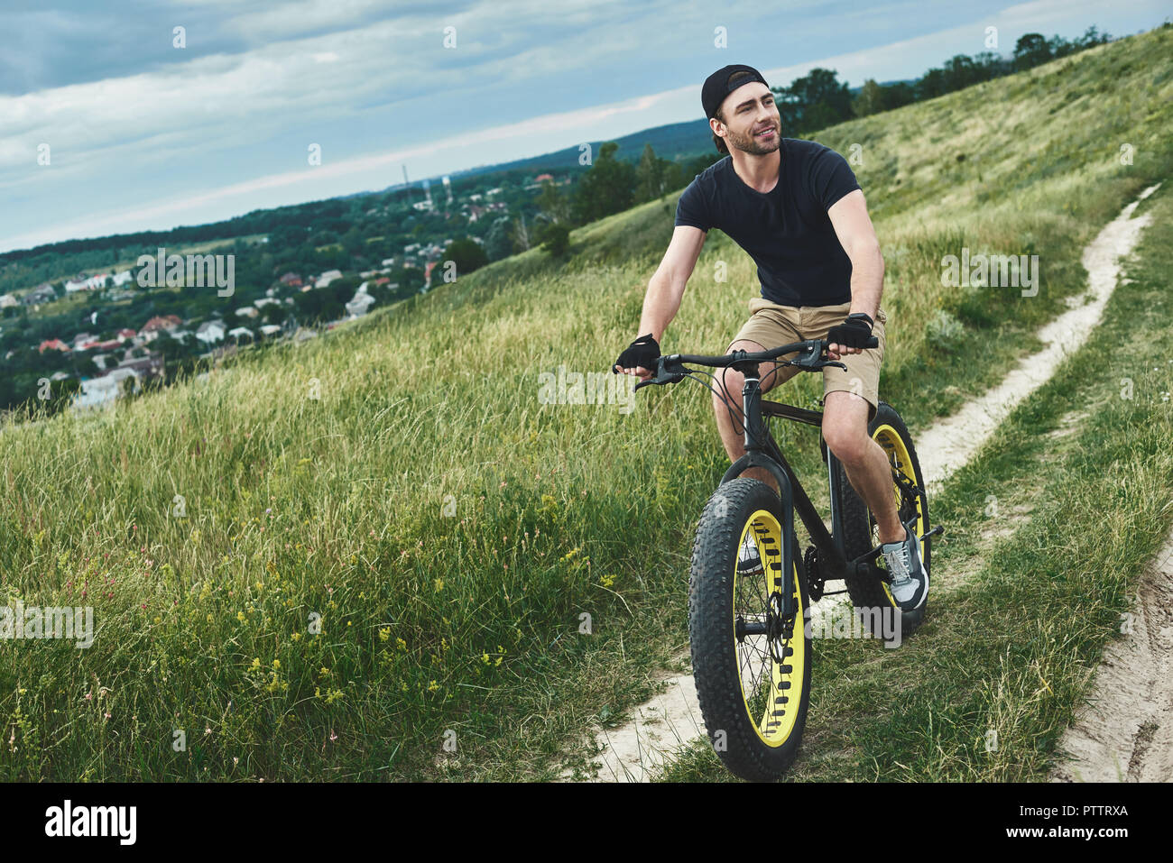 Bel ragazzo elegante escursioni in bicicletta in montagna. Egli ha usato offerte  mountain bike, incredibile cielo Foto stock - Alamy