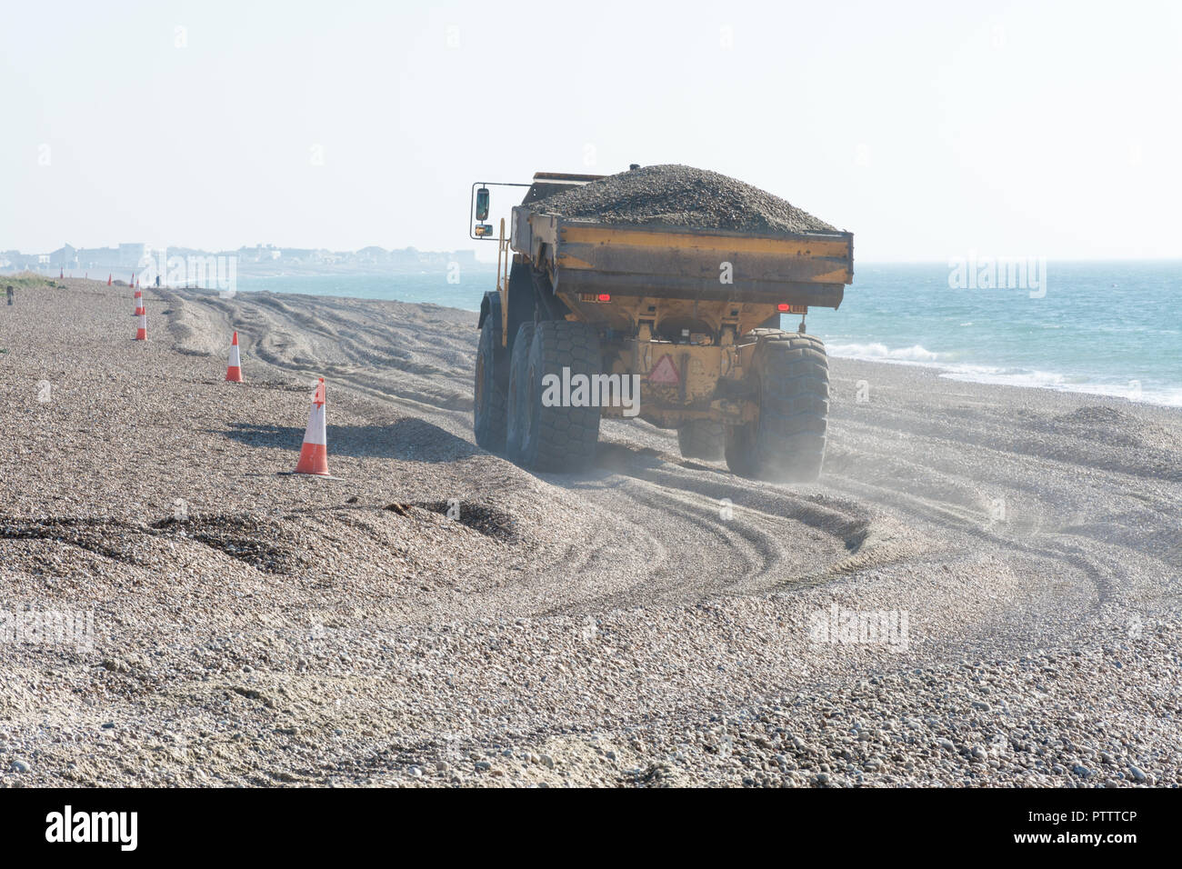 Autocarro pesante cassone di camion di scandole in movimento sulla spiaggia a Hayling Island per migliorare le difese costiere, Hampshire, Regno Unito Foto Stock
