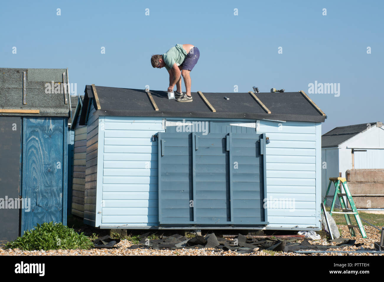 Uomo al lavoro, effettuare le riparazioni sul tetto di una capanna sulla spiaggia Foto Stock