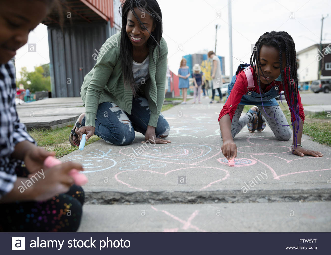 La madre e le figlie colorazione con sidewalk chalk Foto Stock