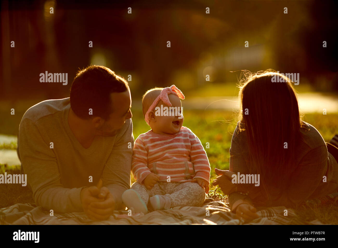 La famiglia felice avente un picnic nel giardino verde Foto Stock