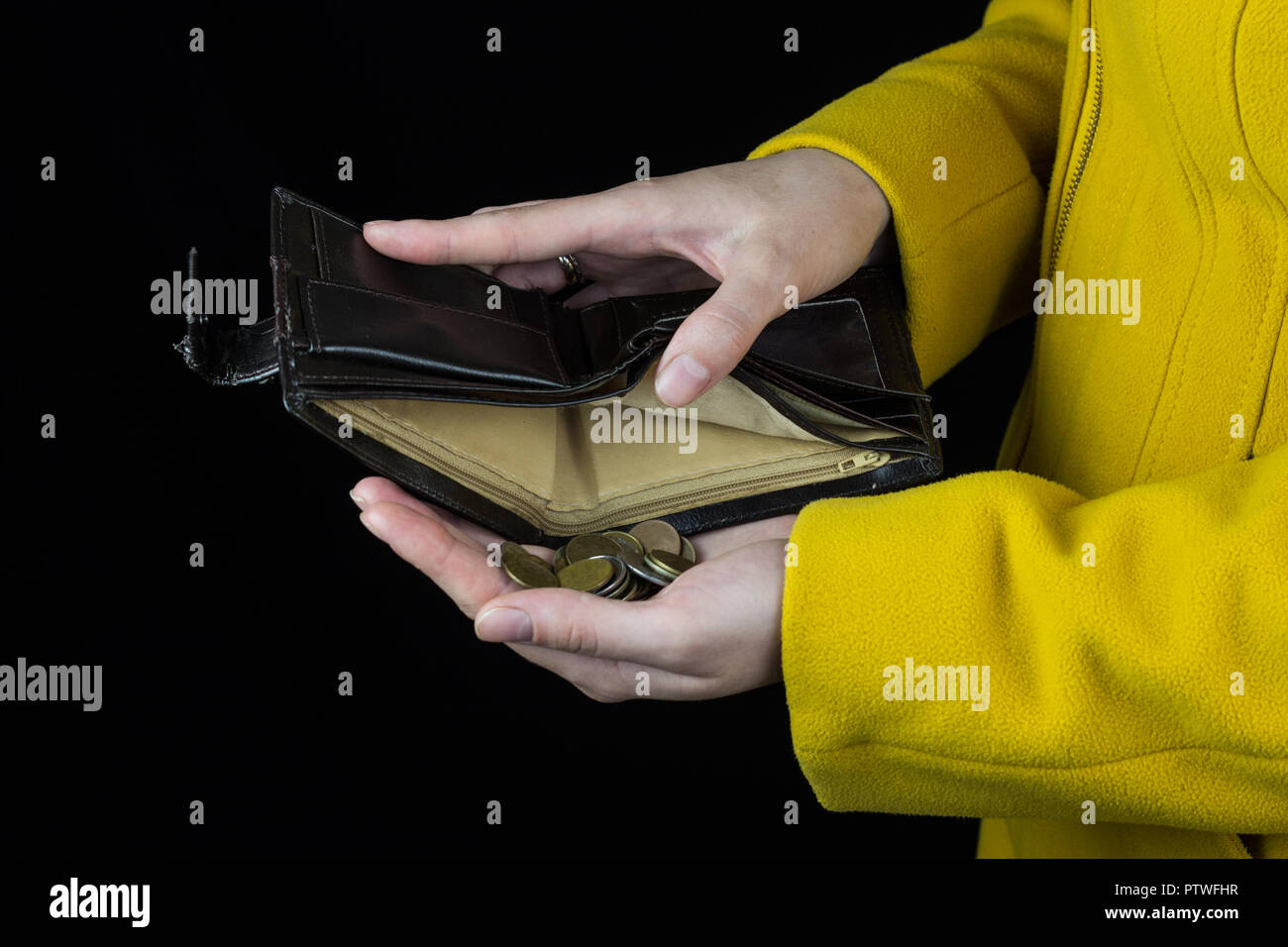 Ragazza versando monete al di fuori di un portamonete, sfondo nero, close-up, coin Foto Stock