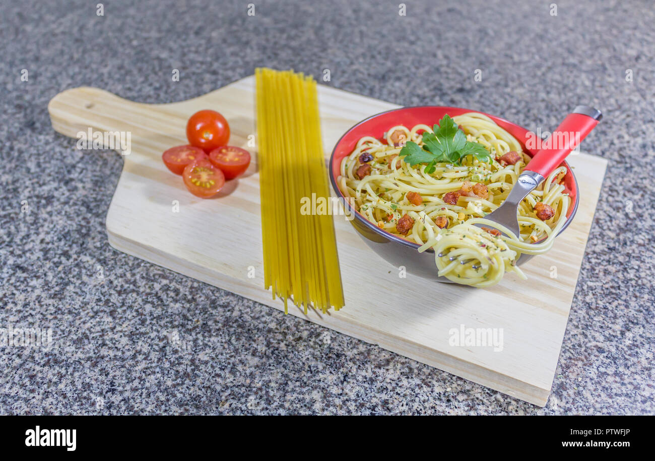 Noodle di aglio e olio, servita in una ciotola con pancetta e pomodori. Foto Stock