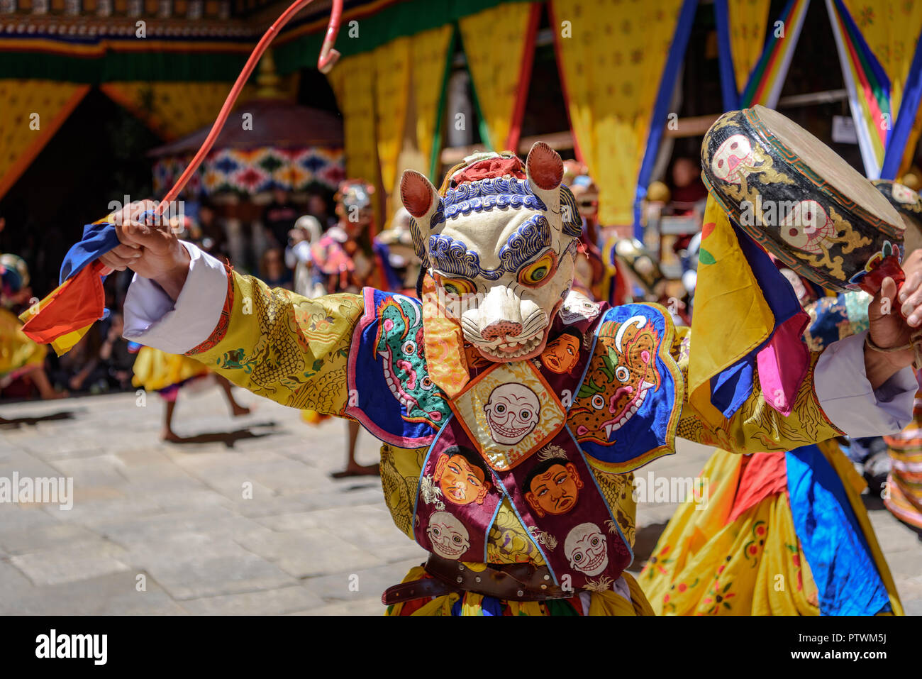 Monaco buddista dancing e tenendo un tamburo a maschera colorata danza al buddismo annuale di Paro Tsechu festival in Bhutan monastero tempio posizione. Foto Stock