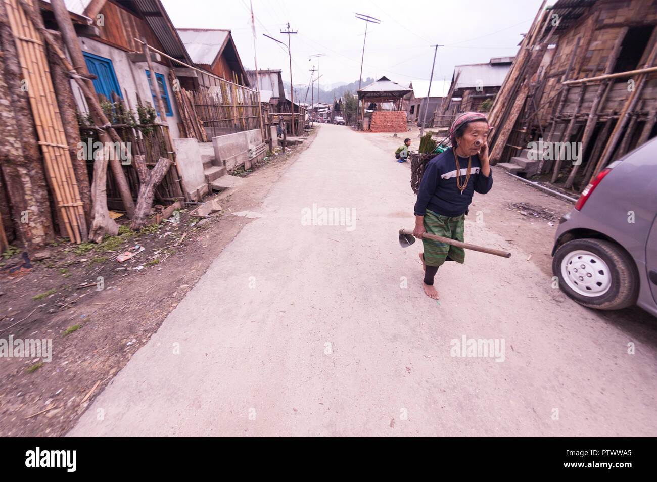 Apatani Tarditional donna,dopo un duro lavoro,tornando a indiani moderni auto,benvenuti lei,vita contrastanti, vecchio villaggio,Ziro,Arunachal Pradesh,NE,l'India. Foto Stock