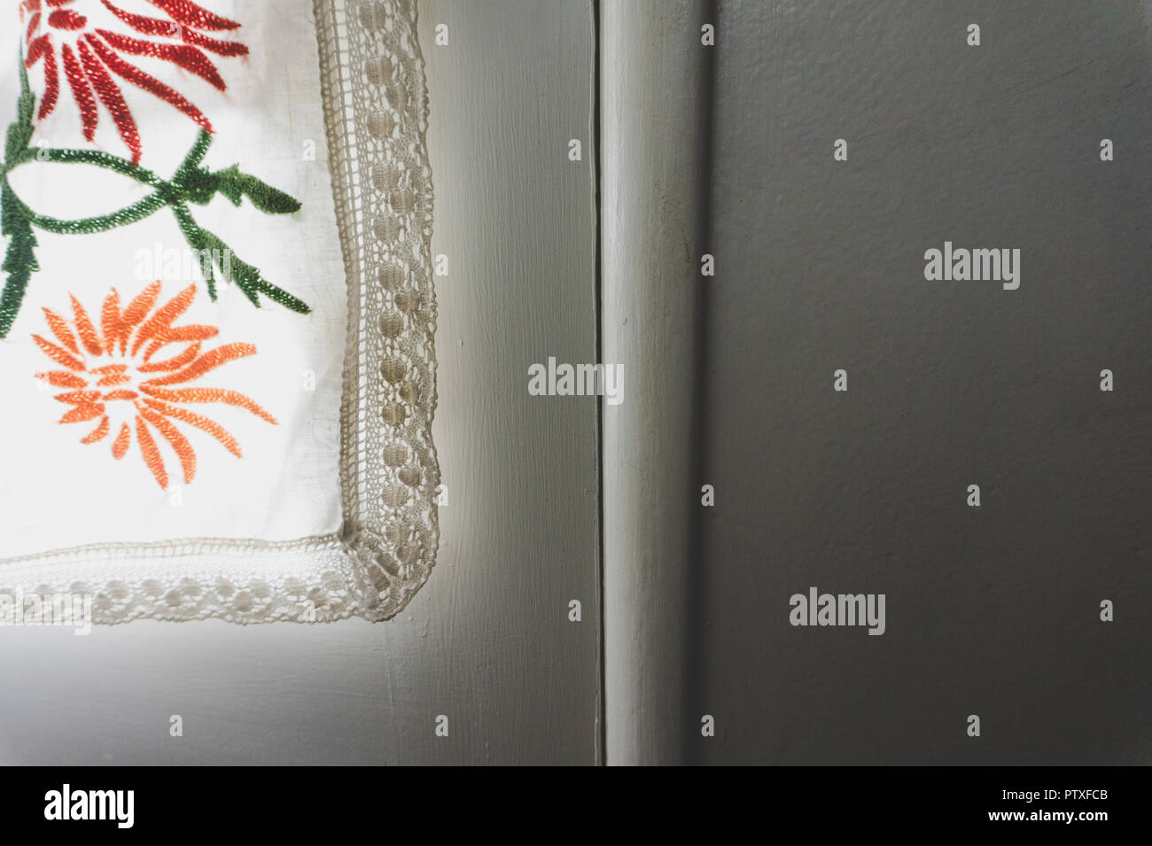 Close-up di Shabby Chic lacey fiorito di tenda illuminata dalla luce del sole contro un muro bianco con una stanza per la copia Foto Stock