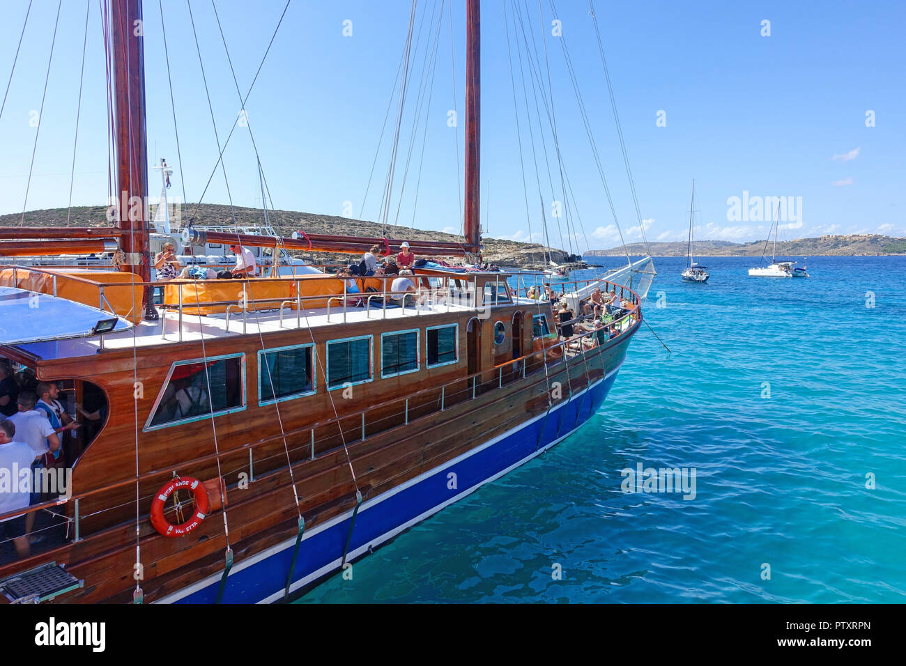 Classico e tradizionale stile-escursione barca ormeggiata in laguna blu, l'isola di Comino. La laguna è famosa per le acque cristalline per il nuoto e le immersioni subacquee. Foto Stock
