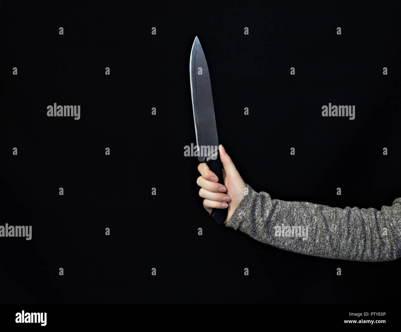 La mano di una ragazza con un coltello su un sfondo nero, close-up, coltello Foto Stock