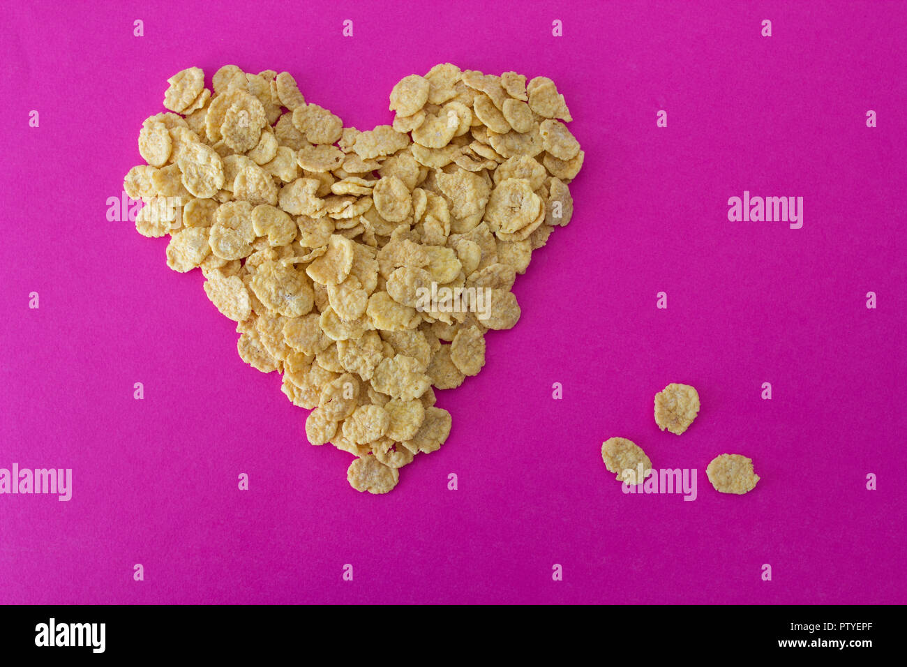 Cornflakes su uno sfondo rosa a forma di cuore Foto Stock