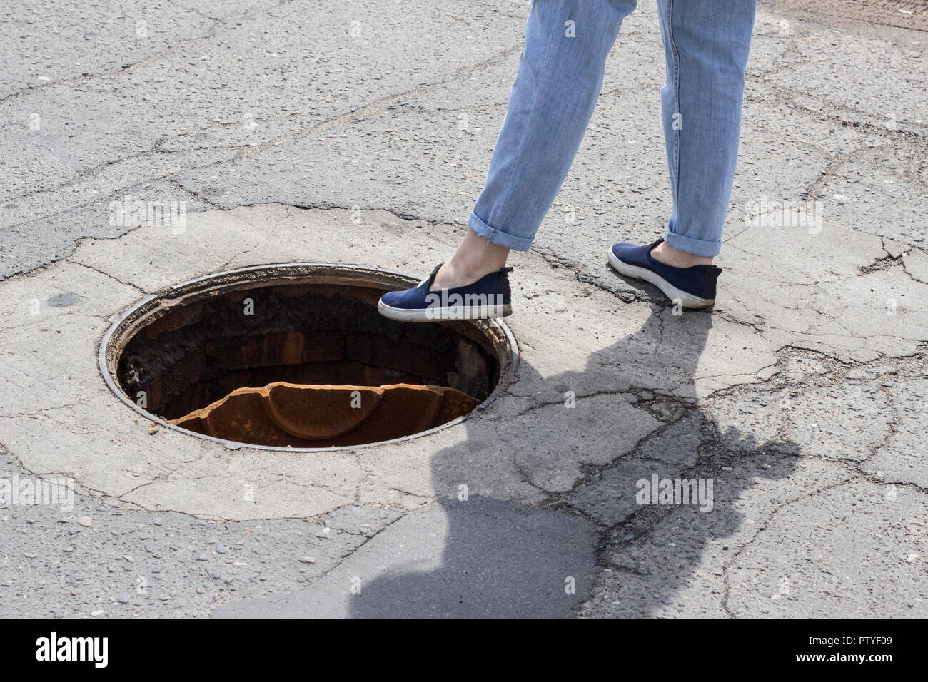 La ragazza passi nel tombino aperto berlina Foto Stock
