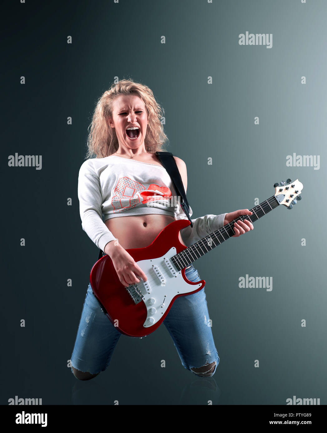 Giovane e bella donna bionda con una chitarra canta una canzone rock Foto Stock