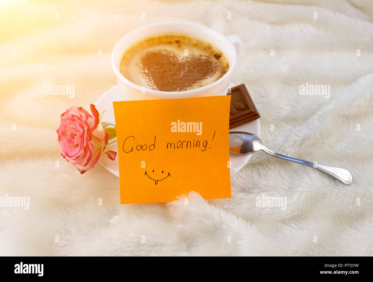 Una tazza di caffè e un cuore di cannella, una rosa, una cioccolata e un adesivo con un buon mattino iscrizione Foto Stock
