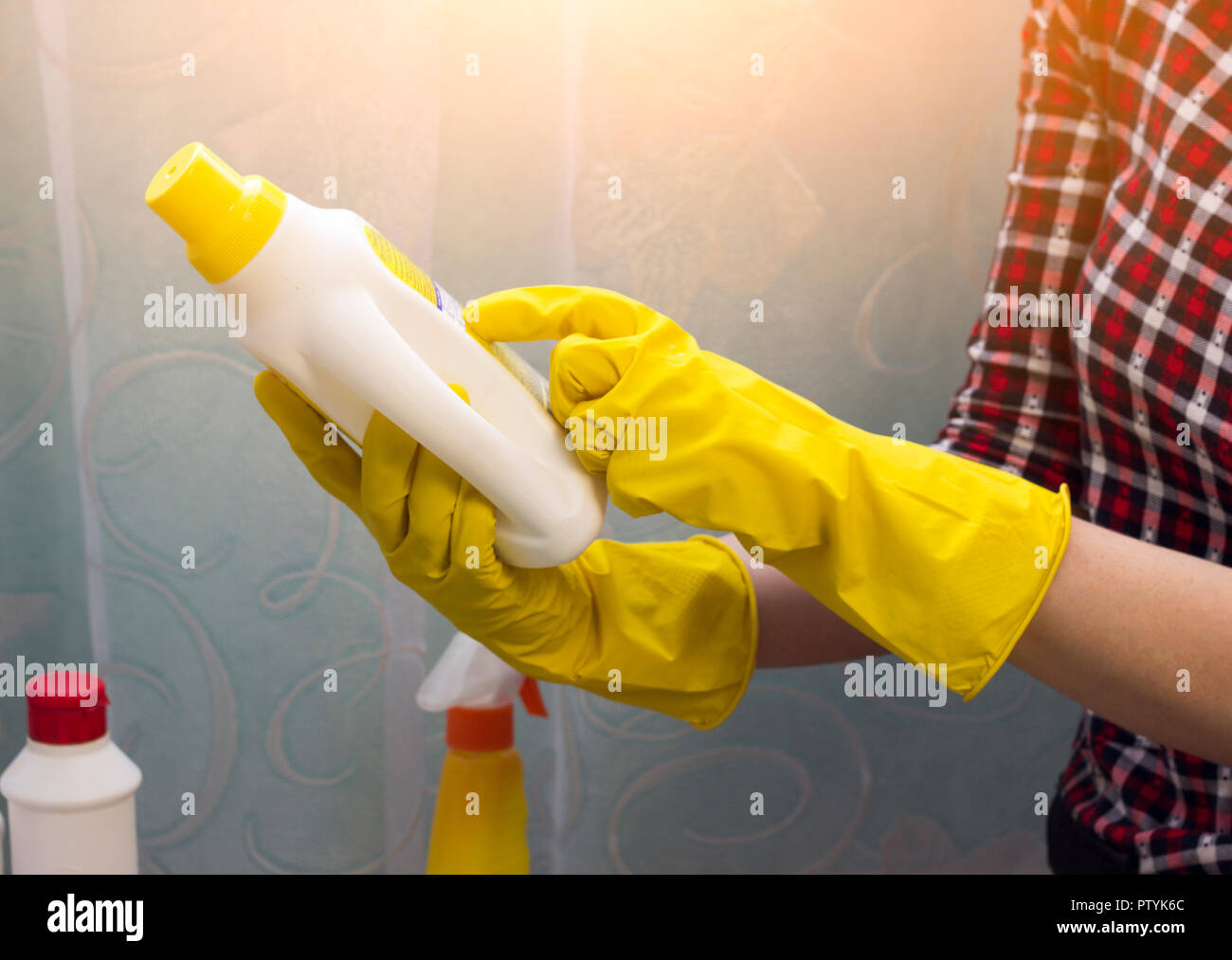 Una ragazza in giallo guanti legge le istruzioni su un pulitore, close-up Foto Stock