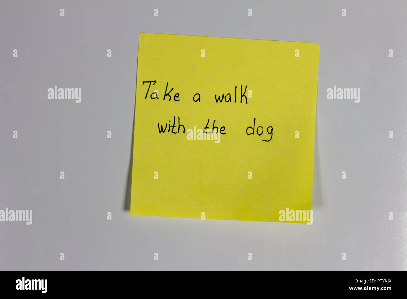 Adesivo giallo sul frigorifero con una iscrizione a fare una passeggiata con il cane Foto Stock