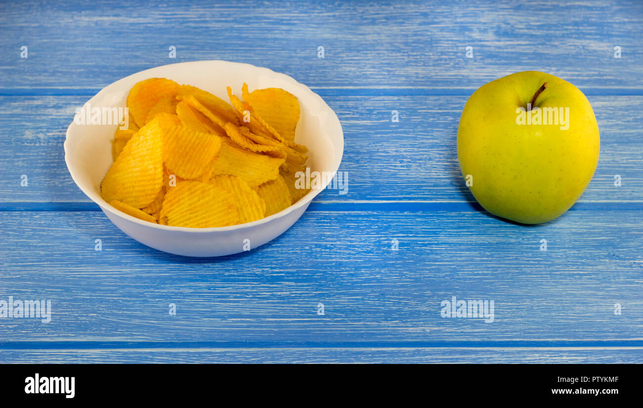 Chip e una mela verde su sfondo blu Foto Stock