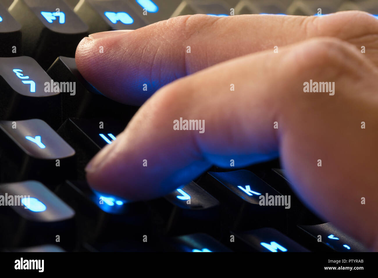 Dita della mano di un uomo digitando su una retroilluminazione della tastiera del computer. Foto Stock