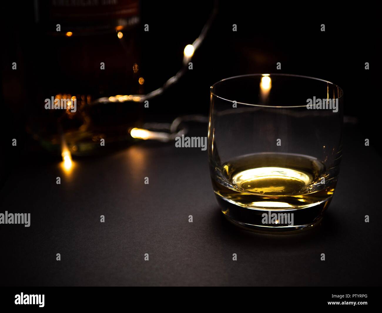 Un romantico, bassa immagine chiave di un bicchiere di whisky con alcune luci fairy in background Foto Stock