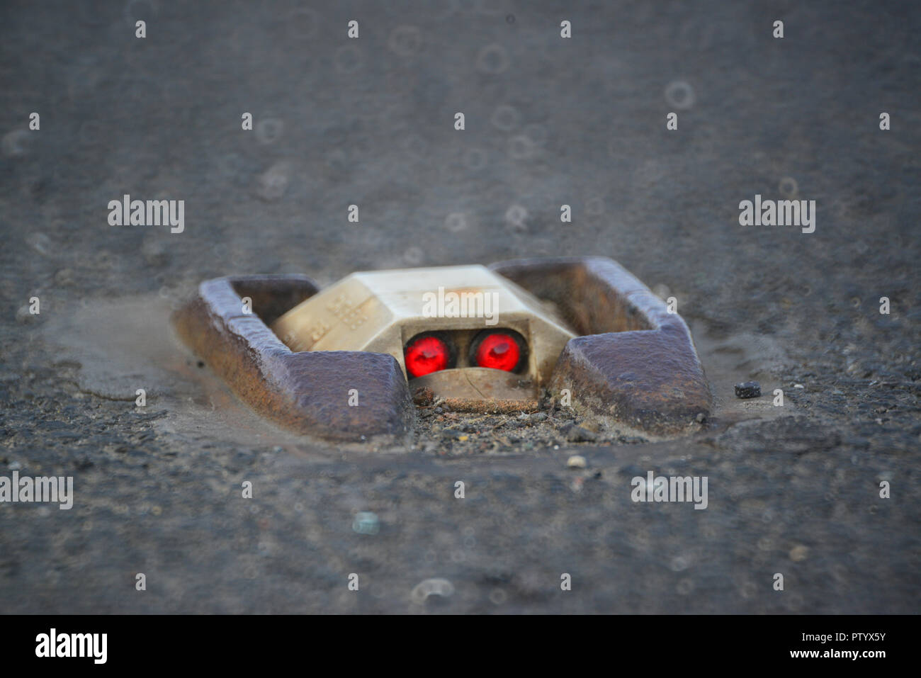 Il traffico che passa gatti occhi riflettendo sulla strada al crepuscolo in leeds Yorkshire Regno Unito Foto Stock