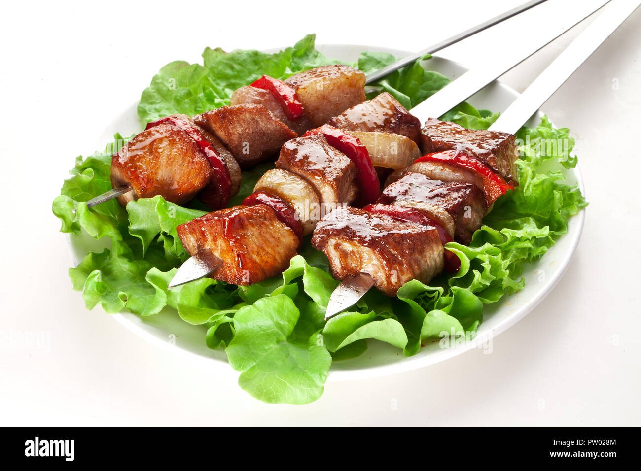 Grigliate di carne e verdure sopra le foglie verdi sulla piastra bianca. Foto Stock