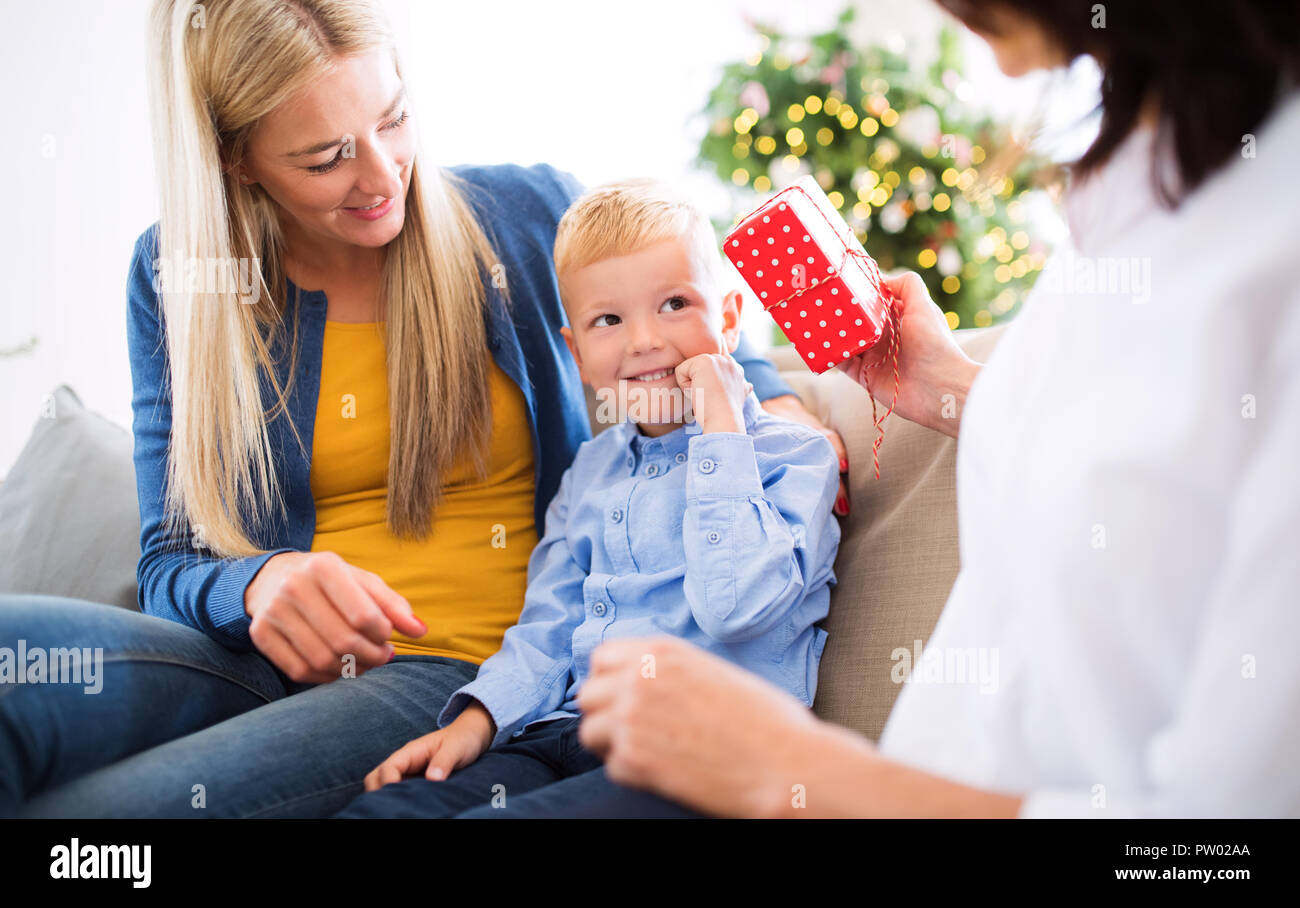 Una madre e nonna dando presente ad un ragazzino di casa al tempo di Natale. Foto Stock