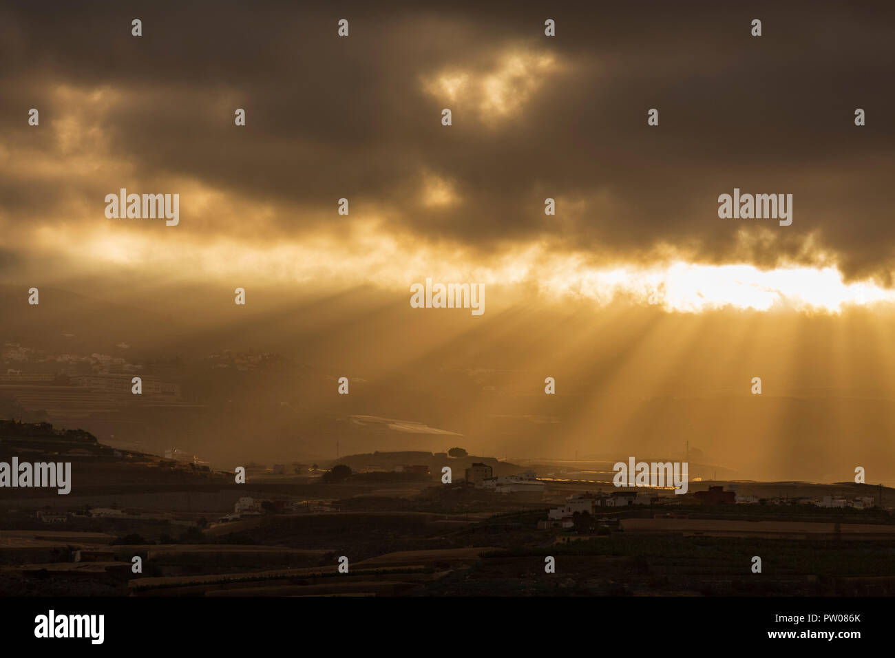 La mattina presto i raggi del sole attraverso la rottura di un divario tra le nuvole illuminando i villaggi di collina nella municipility di Guia de Isora, Tenerife, Canarie ho Foto Stock