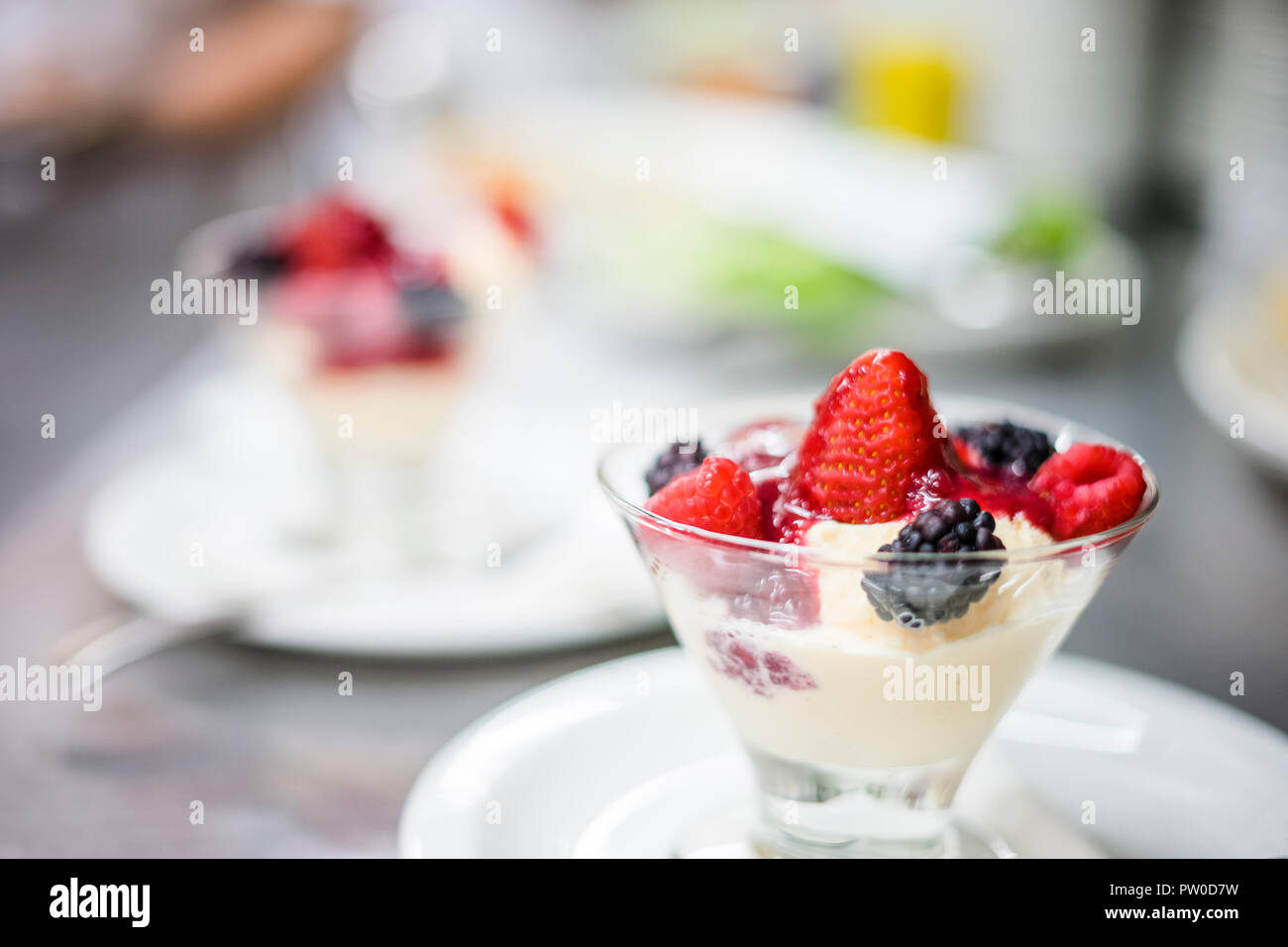 Vaso di vetro pieno di gelato alla vaniglia, frutta e marmellata Foto Stock