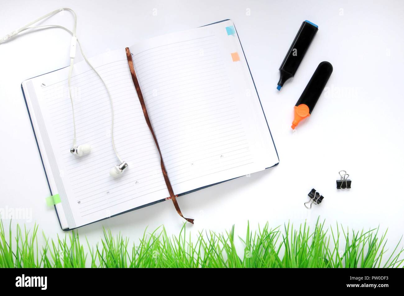 Studio roba. Sfondo dell'istruzione. Articoli di cancelleria. Gli aspetti dell'istruzione. Adesivi, marcatori di clip, cuffie e aperto il notebook sul tavolo con decora Foto Stock