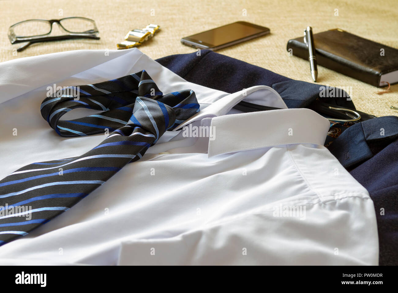 Uomo d'affari abbigliamento accessori e smartphone sul letto. Business man preparando per andare al concetto di ufficio. Foto Stock