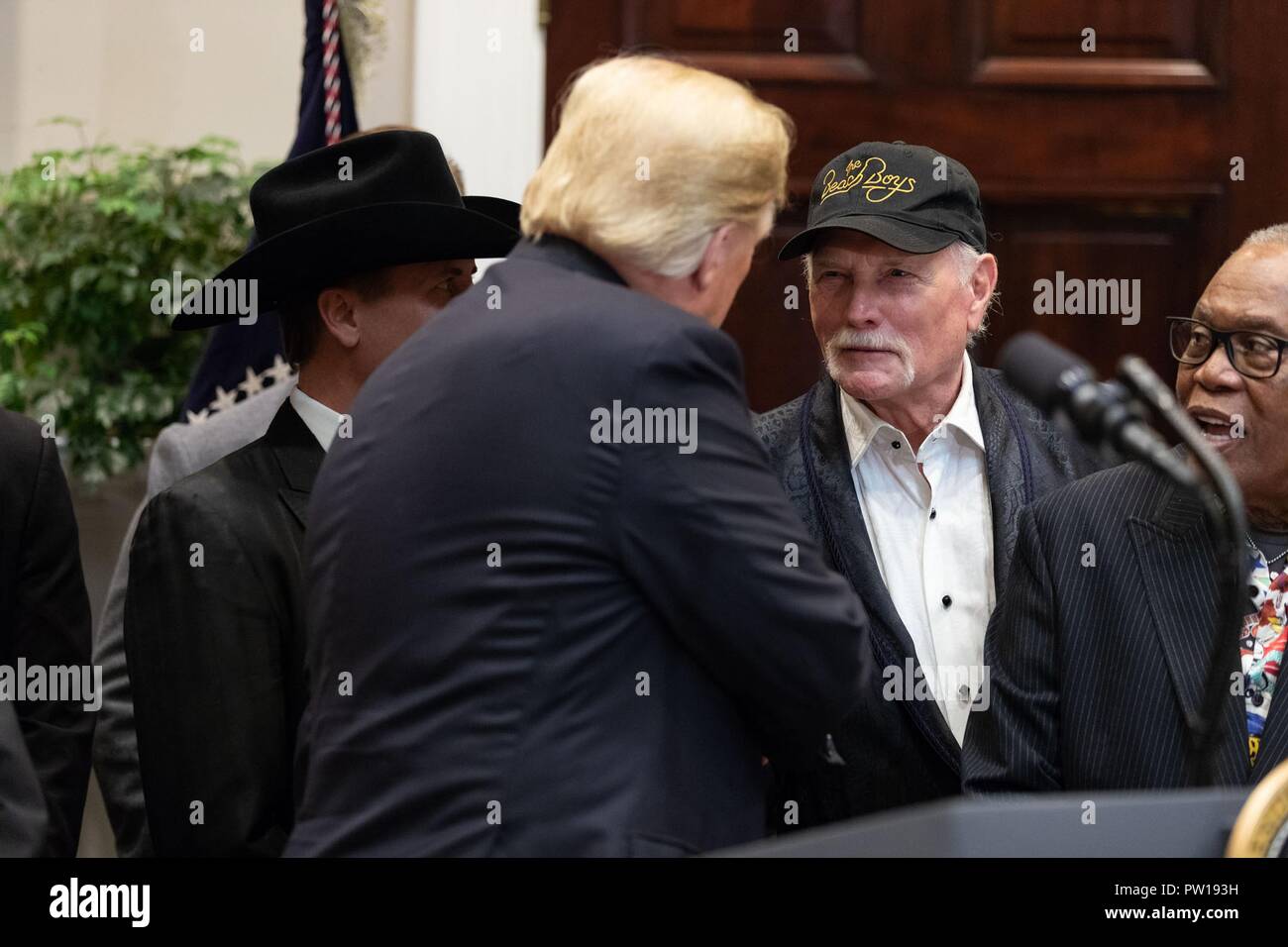 U.S presidente Donald Trump scuote le mani con il musicista Mike Love, dei Beach Boys parla durante una cerimonia di firma la musica Modernization Act nella sala Roosevelt della Casa Bianca Ottobre 11, 2018 a Washington DC. Foto Stock