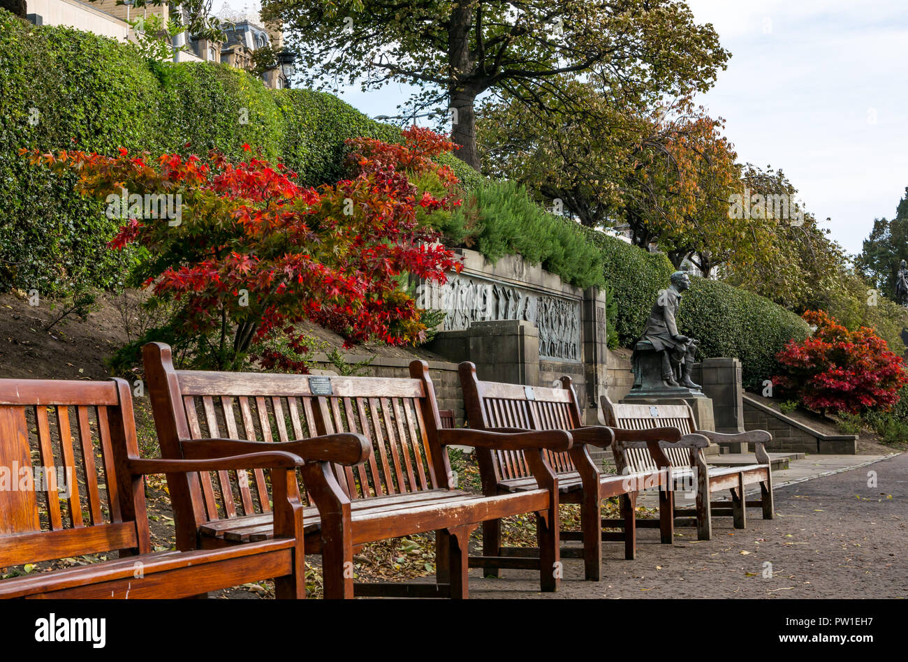 I giardini di Princes Street, Edimburgo, Scozia, Regno Unito, 12 ottobre 2018. Meteo REGNO UNITO: Autunno red maple leaf color legno e panchine a Scottish American war memorial con kilted statua soldato Foto Stock